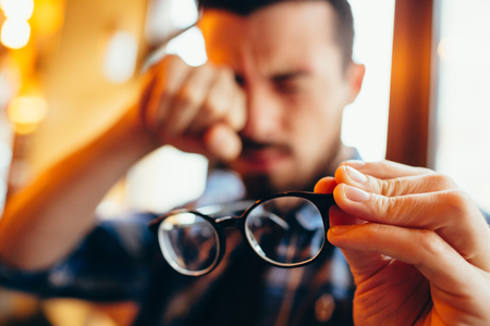 Closeup portrait of young man with glasses, who has eyesight problemsの写真素材