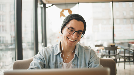 Handsome businessman in casual wear and eyeglasses is using a laptop in cafeの写真素材
