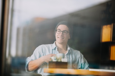Handsome businessman in casual wear and eyeglasses is using a laptop in cafeの写真素材