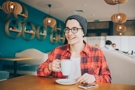 Attractive young man or freelancer is sitting in cafe and drinking tea.の写真素材