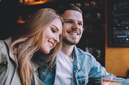 Portrait of positive beautiful young couple in love sitting at a pleasant coffee shop. They are dreaming about their amazing future. Close upの写真素材