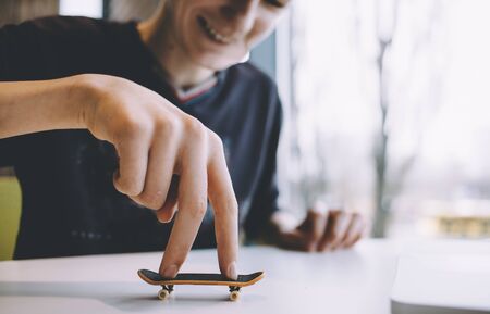 Funny and handsome guy sitting in a nice cafe near the window and playing on the table with a small toy. Smilng man is happy. Close upの写真素材