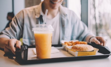 Handsome young man having lunch in elegant cafe alone. Cute guy is going to try his tasty sandwich and french fries. He is ready to start this delicious dish. Close upの写真素材