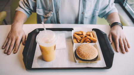 Handsome young man having lunch in elegant restaurant alone. Stylish guy in jeans jacket is going to have tasty and fresh menu. Close upの写真素材