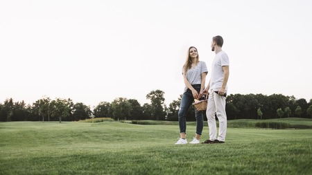 Cool shot of two young people standing besides each other. They are holding a basket of fruits together. This boy and girl had a good day today and spent it with pleasure. But now its time to go home.の写真素材