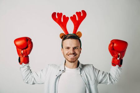 A guy in boxing gloves is waiting for hot packages. Man is determined to break prices. Knocks out discounts. Smiling before a cheap Christmas vacation on a last minute ticket. New Year offer.の写真素材