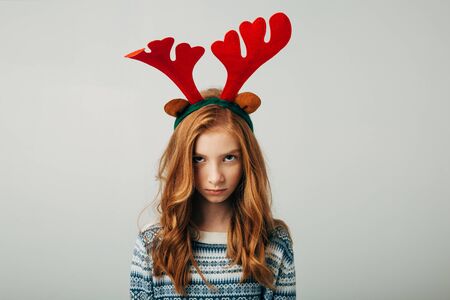 The red-haired girl was very offended by her parents on Christmas evening. Blue-eyed cutie angry at friends with a New Years gift. The teenager is depressed. Teenage mood is changing. Separately on a white background. Family problemsの写真素材