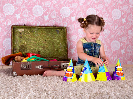 little girl playing with toys on the carpet. nearby is a suitcase with toysの写真素材