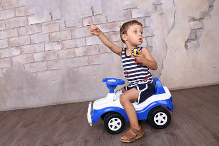 little boy sitting on a toy carの写真素材