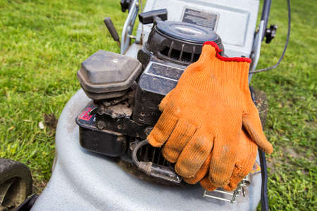 Orange gloves lay on a lawn mowerの写真素材