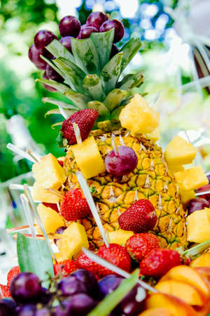 wedding fruit plate on the background of nature. The composition of the fruit pineapple strawberries grapesの写真素材