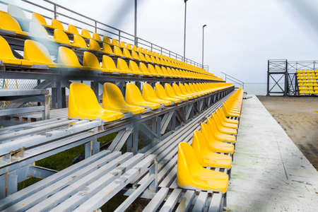 sports yellow benches at stadium. in the background the seaの写真素材