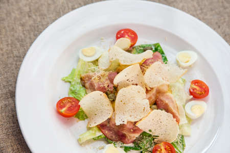 Traditional Caesar salad with croutons, quail egg, bacon and chickenの写真素材