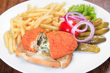 on the table a plate of chicken Kiev with fried potatoes, pickled cucumber, pickled tomatoes, onions. top viewの写真素材
