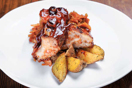 on the table is a plate of grilled ribs, stewed cabbage, baked potatoes and salad letukの写真素材