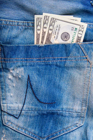 $ 20 bill in the pocket of jeans, jeans neatly stacked on wooden background, top viewの写真素材