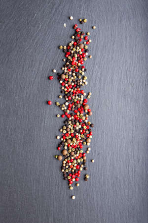 colored peppers scattered on the slate, top view