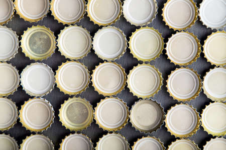upturned caps of beer lined up in rows, top viewの写真素材