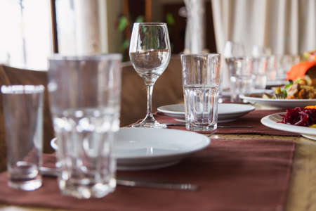 a holiday served table, on the table are empty glasses and plates in the background are a treat, closeupの写真素材