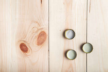 three caps from beer on a wooden board, top viewの写真素材