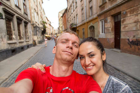 selfie man and woman on the street of Lviv. There are few people on the backgroundの写真素材