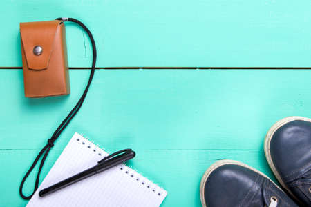 On a wooden turquoise surface lies a notebook, running shoes, camera. Notes on the road. Set...