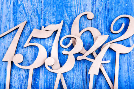 wooden numbers one, two, three, four, five, six, seven, scattered on a blue wooden background, top...