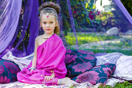 small European girl in oriental dress, crimson color, in a tent outdoors, harmony, staged shooting