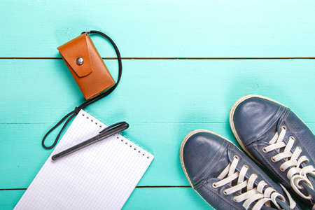 On a wooden turquoise surface lies a notebook, camera. Notes on the road. Set journalist. view from aboveの写真素材