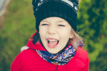 cute girl in a red jacket and cap in the street, girl indulges and ape