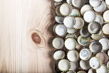 a lot of beer caps on a wooden board, top viewの写真素材