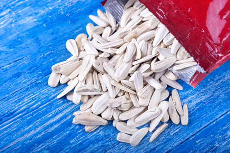 white sunflower seeds in open packaging, on wooden backgroundの写真素材