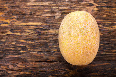 a whole ripe melon on a dark brown table