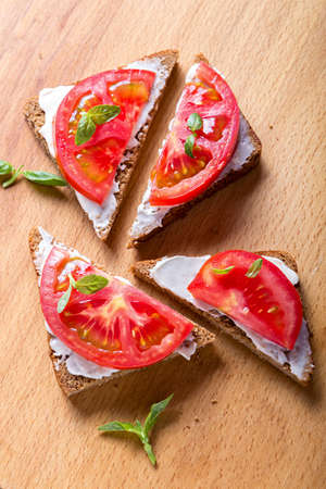 summer sandwiches with tomato and basil on a wooden surface.の写真素材