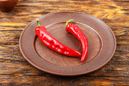 red pepper in a clay plate on dark wooden surfaceの写真素材