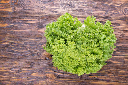 lettuce in a clay plate on a wooden table, top viewの写真素材