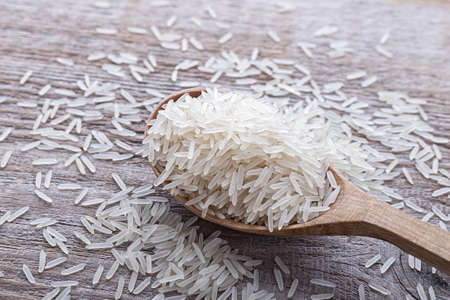 raw rice in a wooden spoon on a wooden backgroundの写真素材