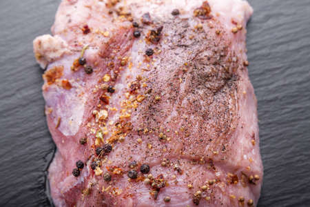raw meat of pork for roasting or barbecue with spices, on a black background, with space for textの写真素材