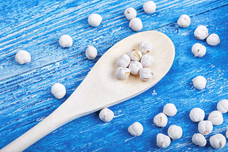 spilled chickpeas on a blue wooden background, lies next to wooden spoonの写真素材