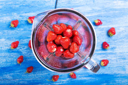 Fresh strawberries in blender cup  on a wooden table. Selective focusの写真素材