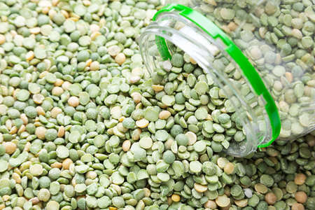 uncooked dry peas is scattered as a background, in the center there is a plastic bankの写真素材