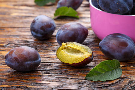 Ripe plums on a brown wooden table, healthy food, summer crop.