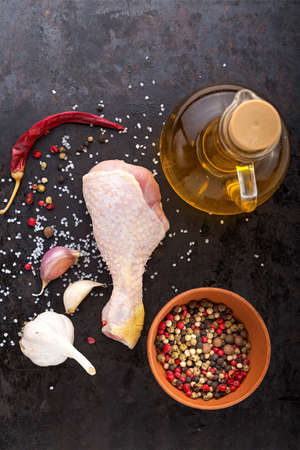 raw chicken leg with spices, oil and garlic on a black background, top viewの写真素材