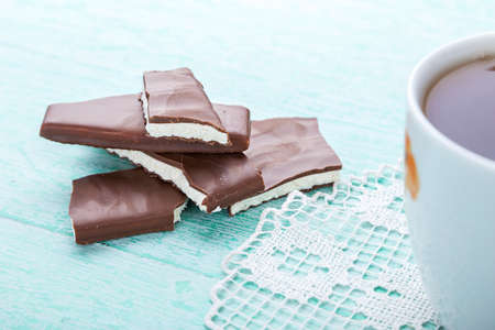 standing on a wooden background cup of tea on lacy napkin beside lie pieces of chocolateの写真素材