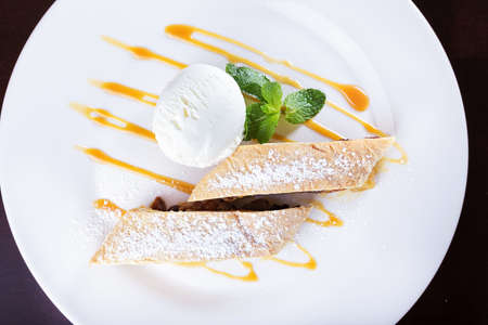 apple strudel with ice cream, dusted with powdered sugar and garnished with mintの写真素材