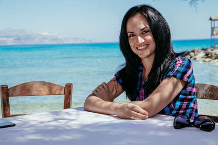 girl at the table in a cafe on the background of the sea, Crete, Greeceの写真素材