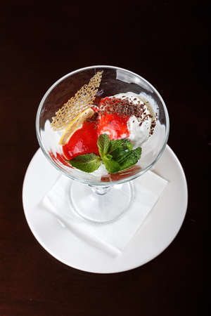 ice cream in a glass with berry topping, lemon slice, chocolate chips and mint. Horizontal photoの写真素材