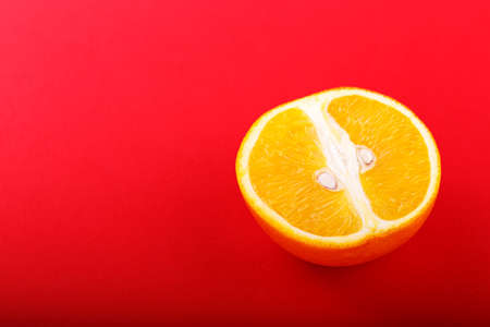 Half of the cut juicy orange on a bright red background, horizontal photoの写真素材