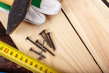 Nails on a log, next to carpenter's working gloves, horizontal photo