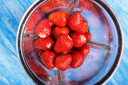 Fresh ripe strawberries in a blender, on a wooden background.の写真素材